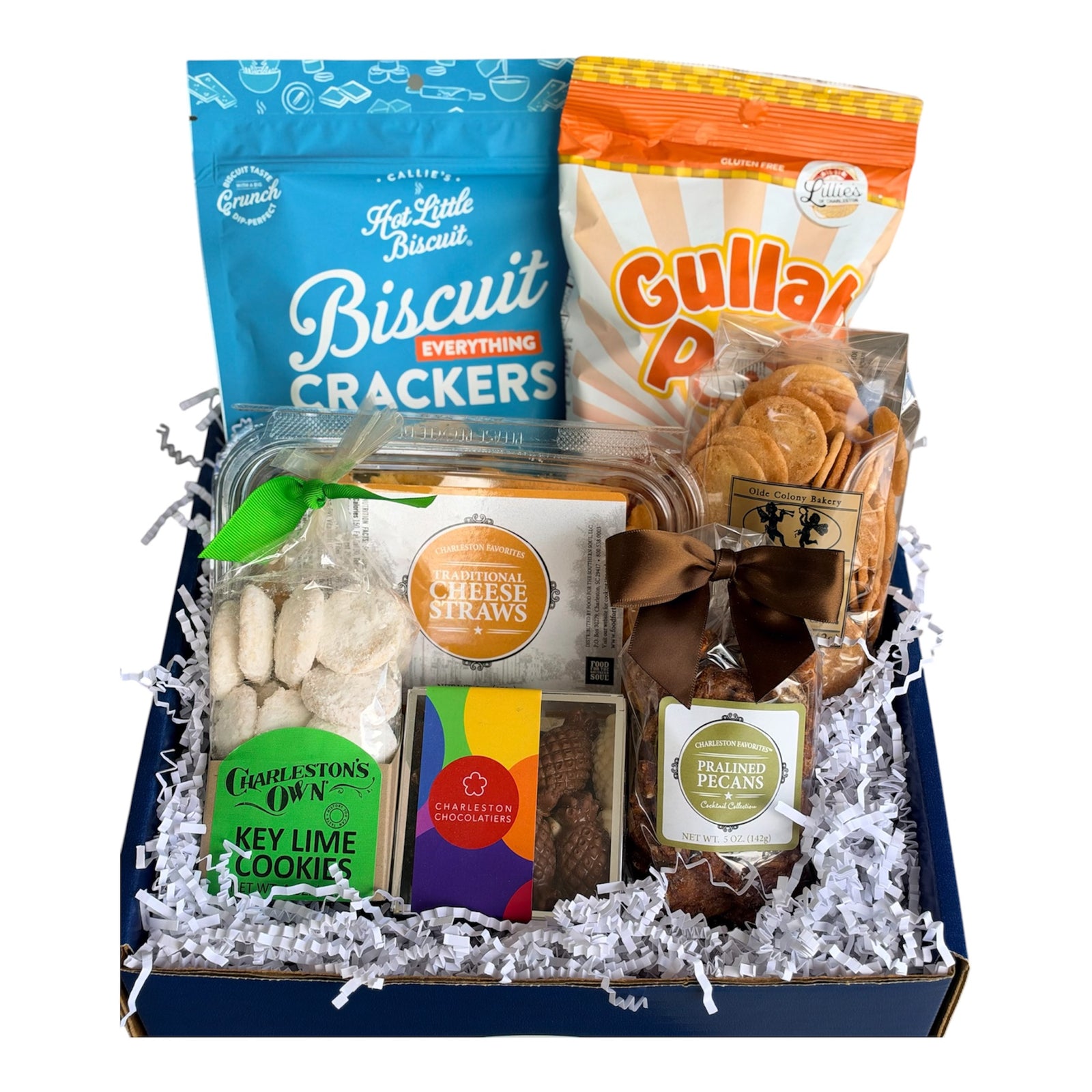 Holy City Snack Sampler with Callie's Hot Little Biscuit Everything Biscuit Crackers, Lillie's of Charleston "Ho Lotta Hissy Fit" Gullah Pop, Olde Colony Bakery Benne Wafers, Charleston Favorites Cheese Straws, Charleston Chocolatiers "Hospitality Pineapple" Chocolate Box, and Charleston Favorites Praline Pecans packed in a branded blue Essentially Charleston gift box.