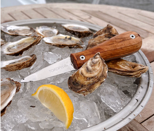 Oysters on ice with a Toadfish Olive Wood Oyster Knife and lemon wedge on a metal tray.
