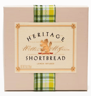 A box of Heritage Lemon-Infused Shortbread, wrapped with a green and white plaid ribbon and featuring a central cream-colored label with a lion crest. - Essentially Charleston